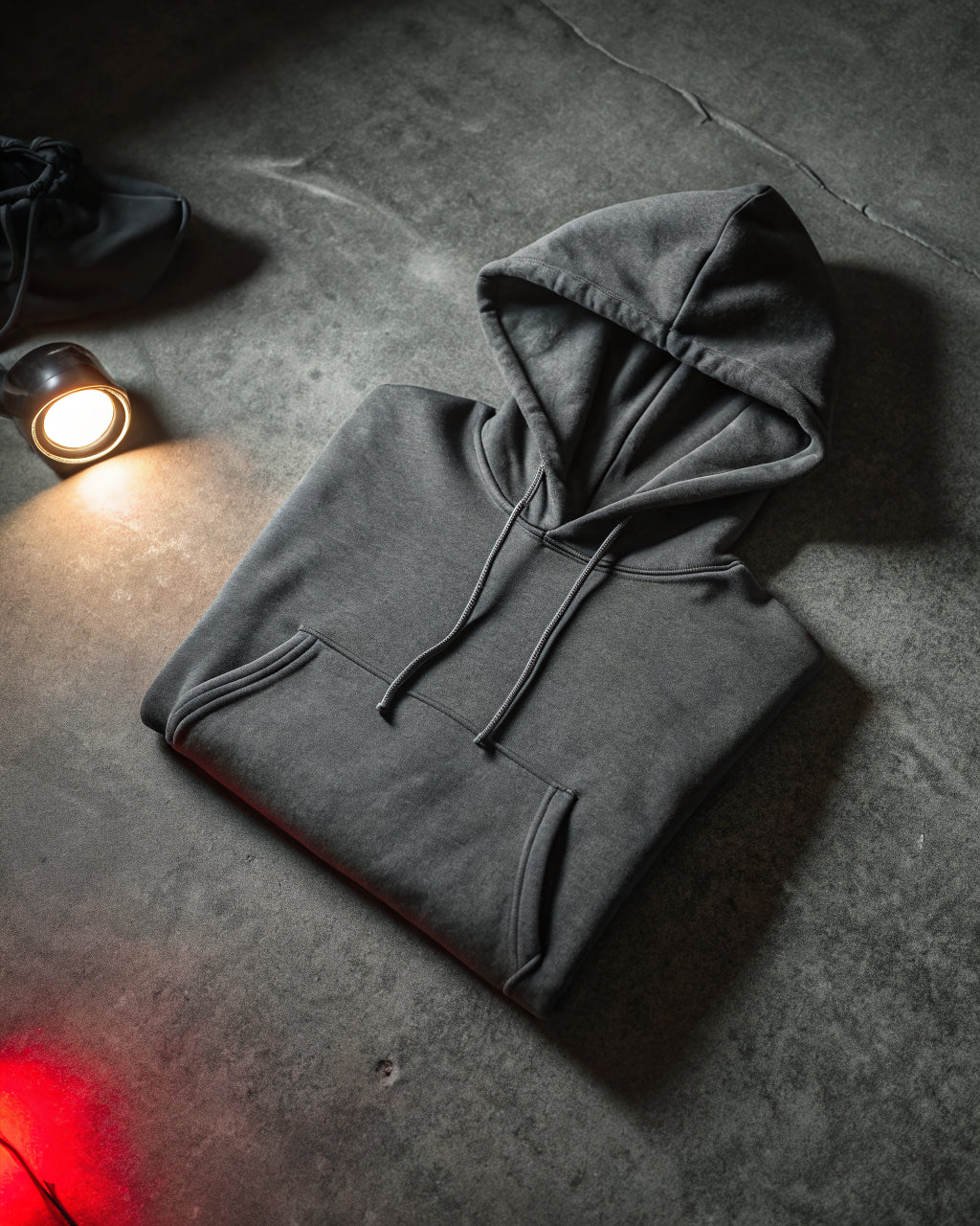 Folded heavyweight charcoal hoodie on dark concrete